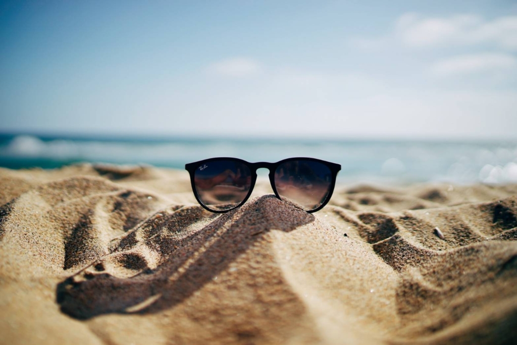 砂浜に置かれたレイバンのサングラスの写真